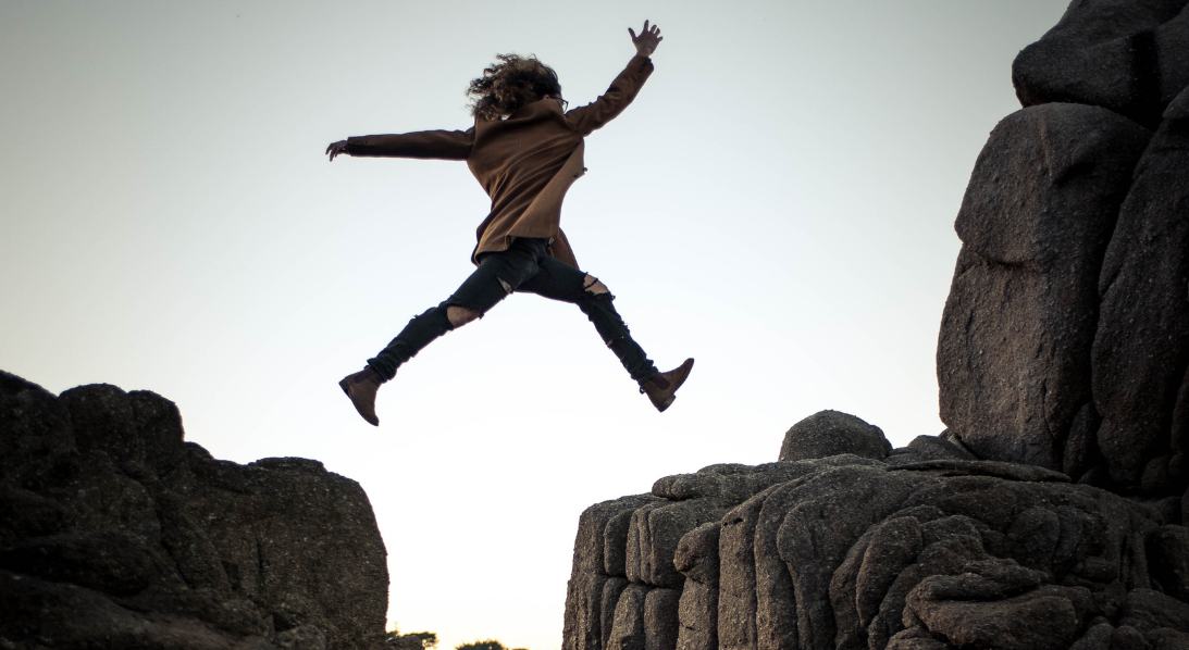 Person leaping over rocks